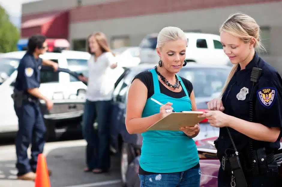 how to get a police report after car accident, image of woman writing down information for police officer on clipboard. Disparti Law Group