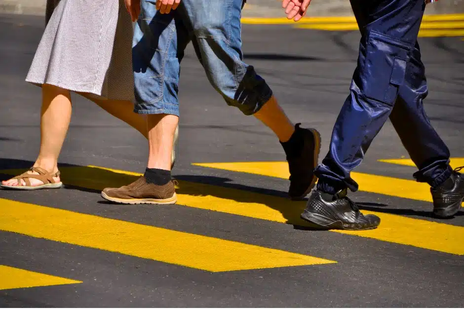 Pedestrian right-of-way laws, image of 3 people from waist up crossing a yellow cross walk, Disparti Law Group