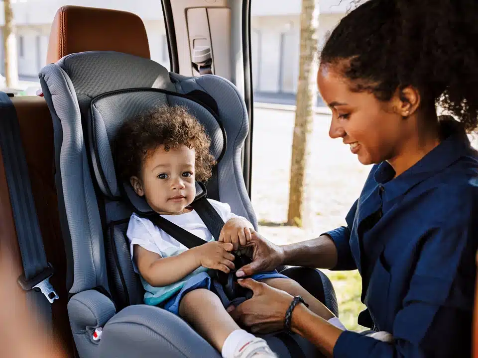 Illinois car seat laws, image of mother strapping child into front facing car seat, Disparti Law Group