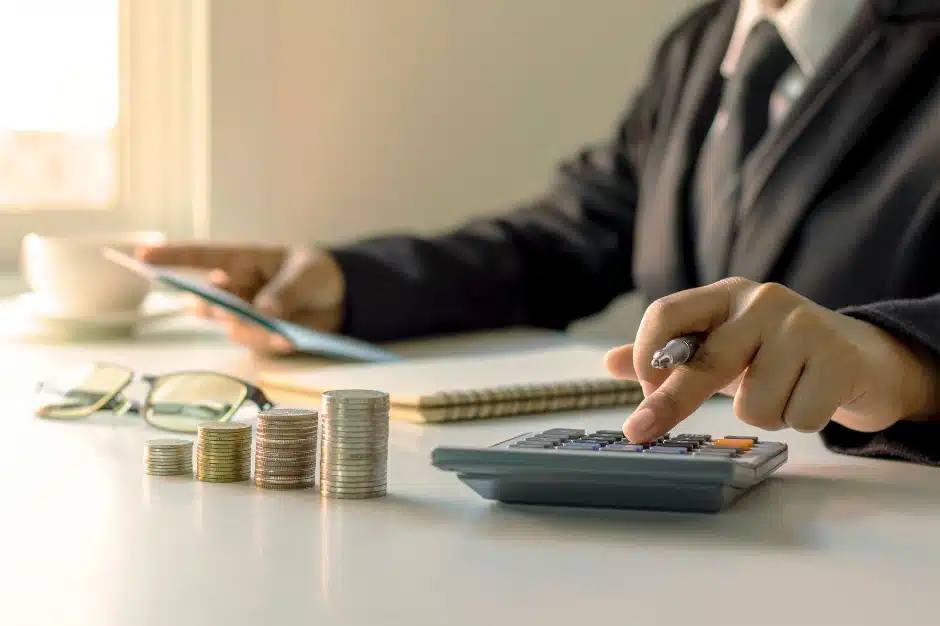 How insurance companies calculate a settlement offer, image of person in suit using calculator near stacked coins, Disparti Law Group 